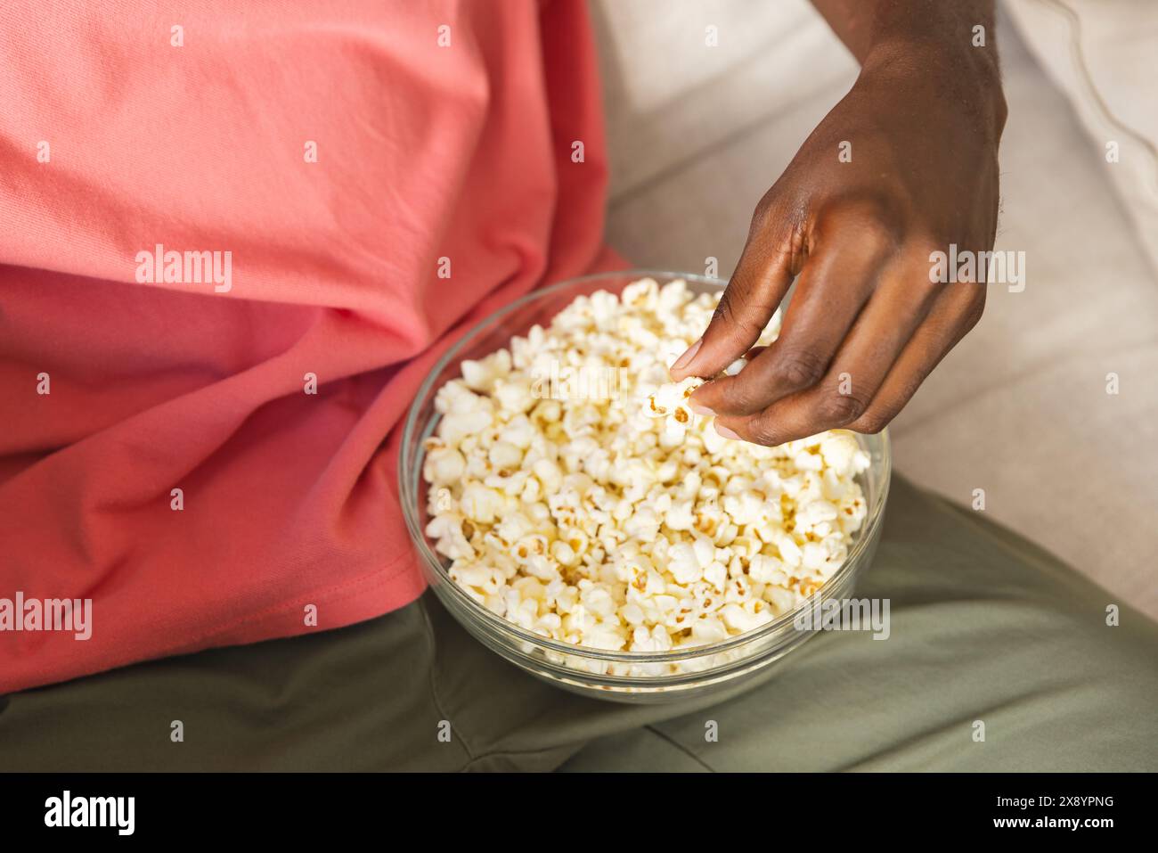 African American man relaxing at home, eating popcorn Stock Photo