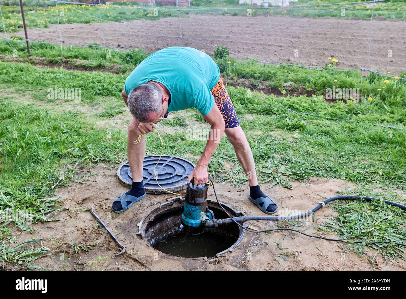 Worker pumping sewage waste from septic tank with wastewater pump ...