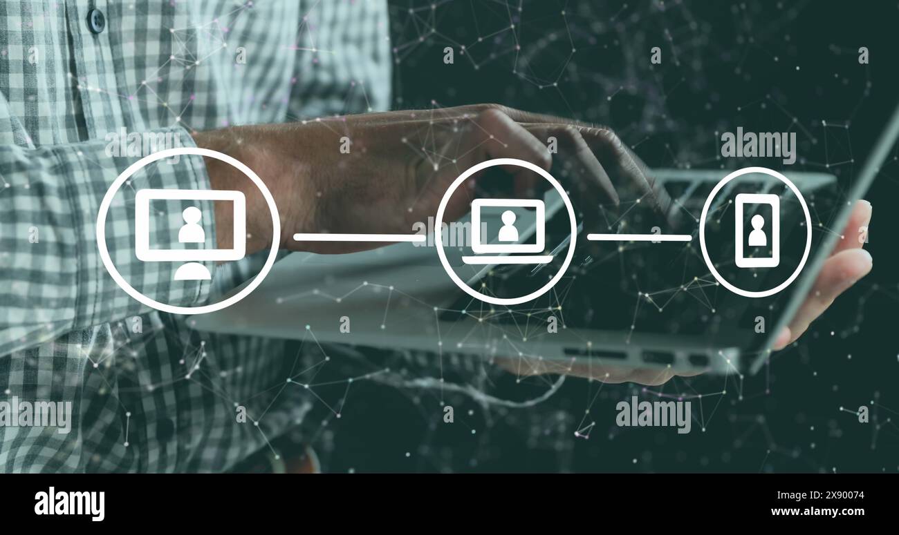 A man is using a digital tablet while standing against a black background Stock Photo