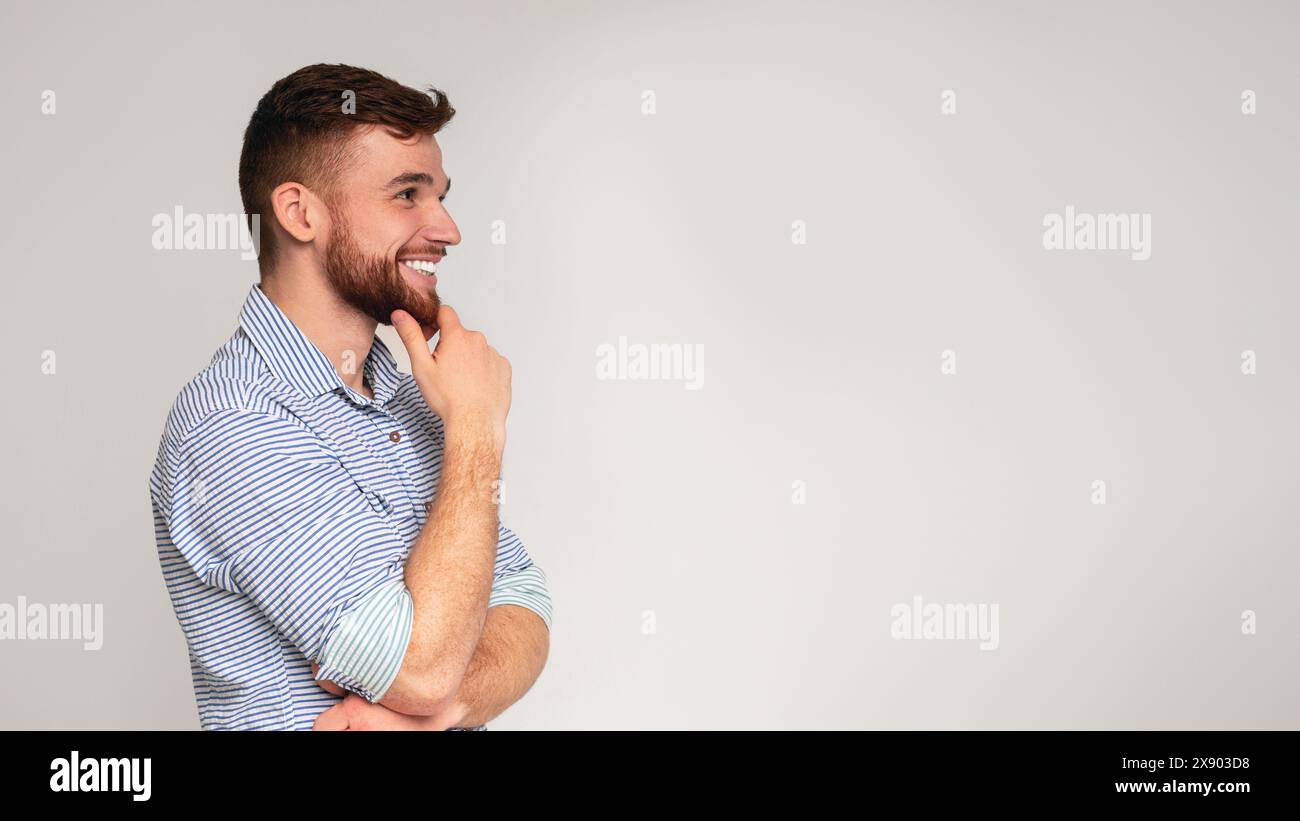 Young smiling man thinking and looking away on free space Stock Photo