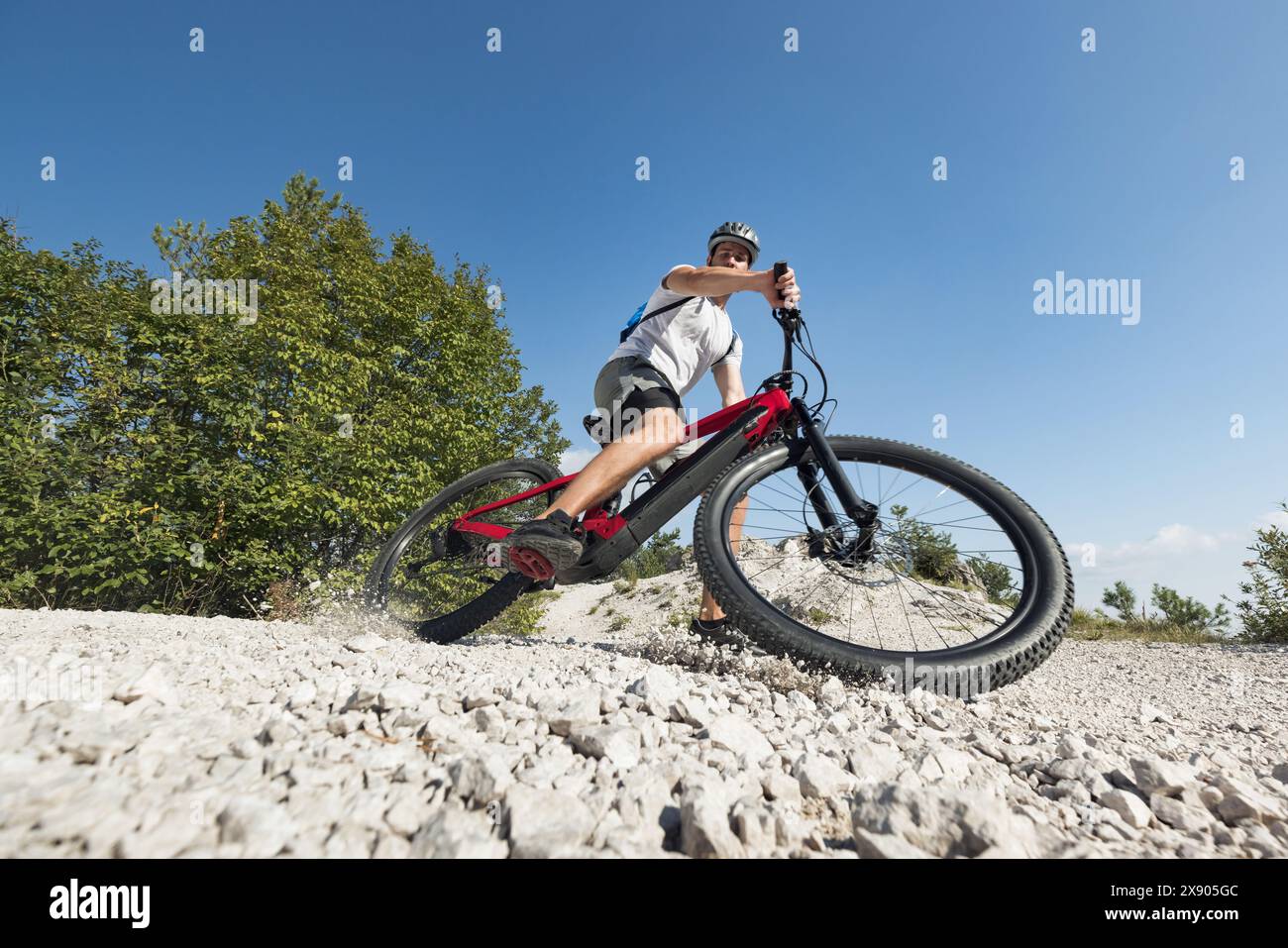 Male electric mountain bike rider going downhill and braking on a hilly