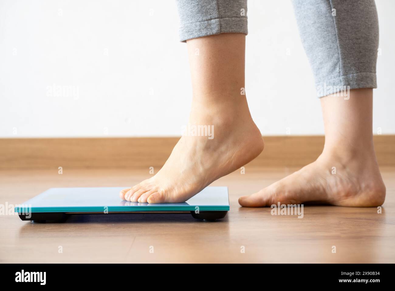 Close-up of a female checking kilogrammes getting on the scale - self care and body positivity concept,profile view Stock Photo