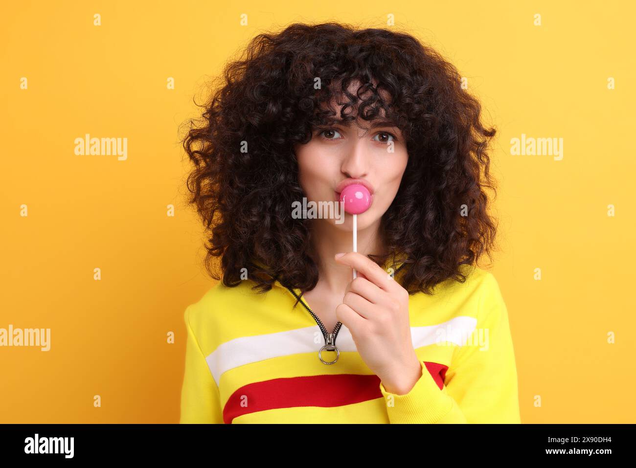 Beautiful woman with lollipop on yellow background Stock Photo