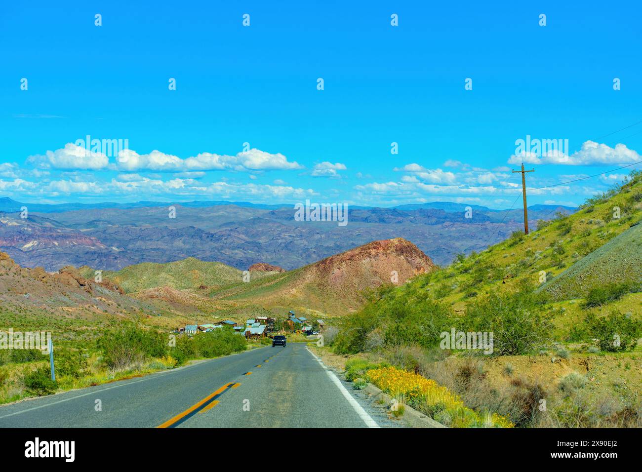 Asphalt road leads the way to an abandoned settlement nestled in the heart of the Nevada desert, surrounded by arid landscapes and rugged terrain. Stock Photo