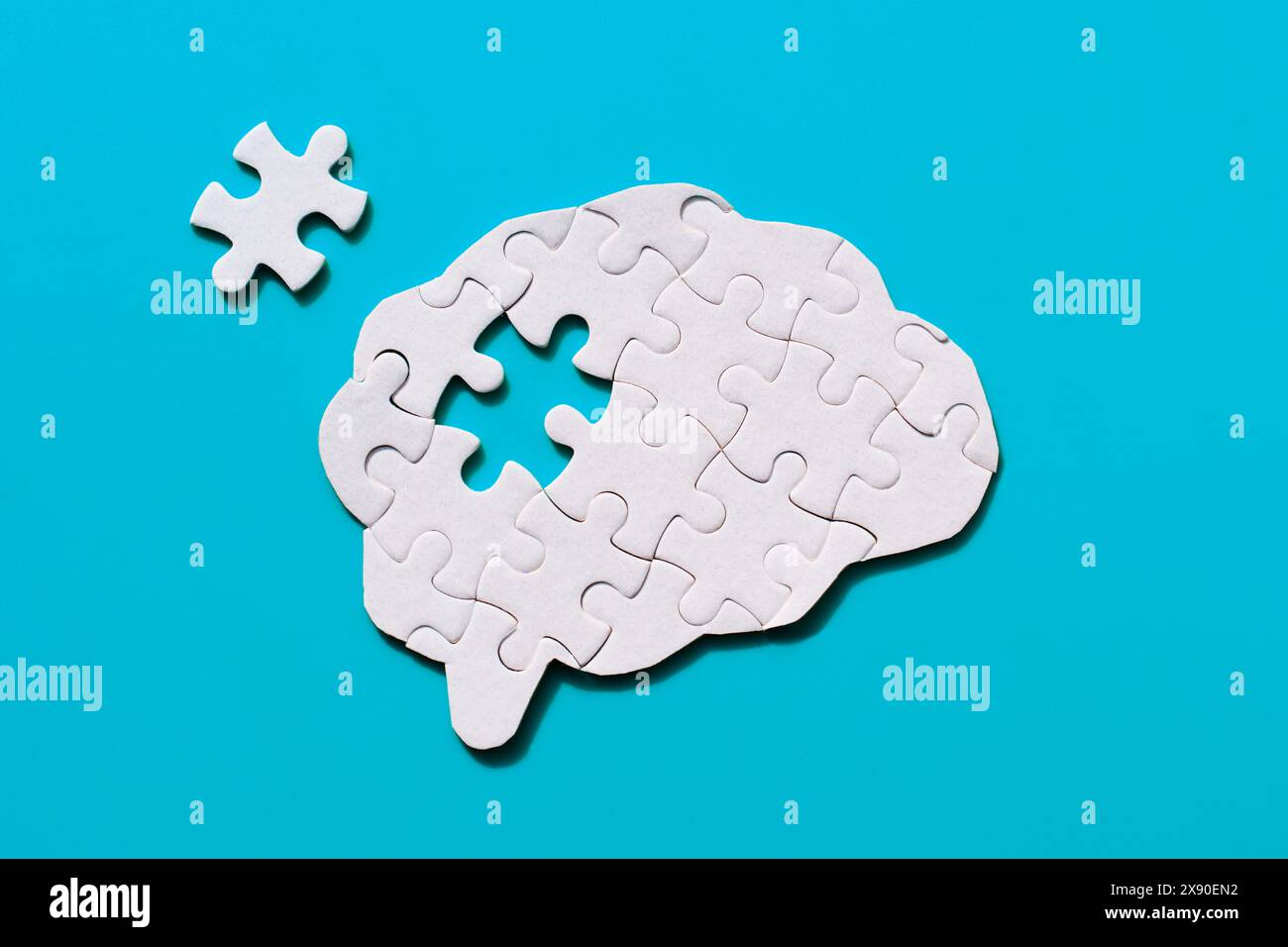 Incomplete jigsaw puzzle in the shape of a brain on a blue background ...