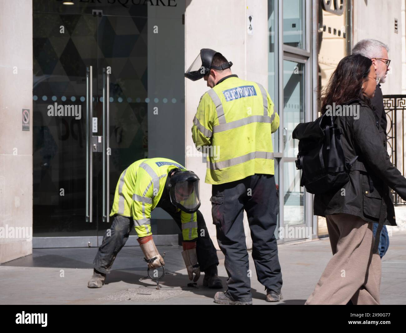 Electricians  lifting removing manhole cover,  access cover,  from street in London Stock Photo