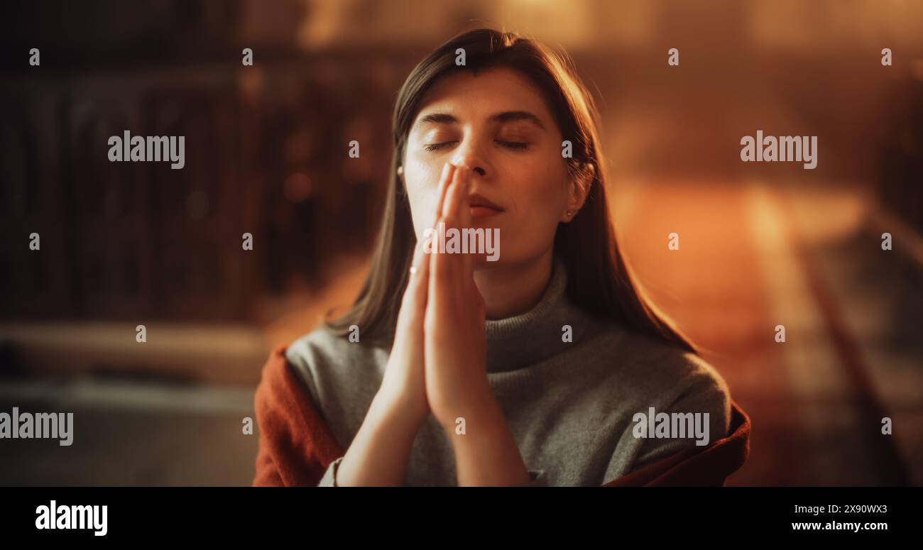 Devout Praying Christian Woman, Bowing In Humble Reverence To God. With Hands Folded She Looks Upwards Before Closing Eyes. Seeking Guidance and Strength to Live a Life in Accordance with The Bible Stock Photo