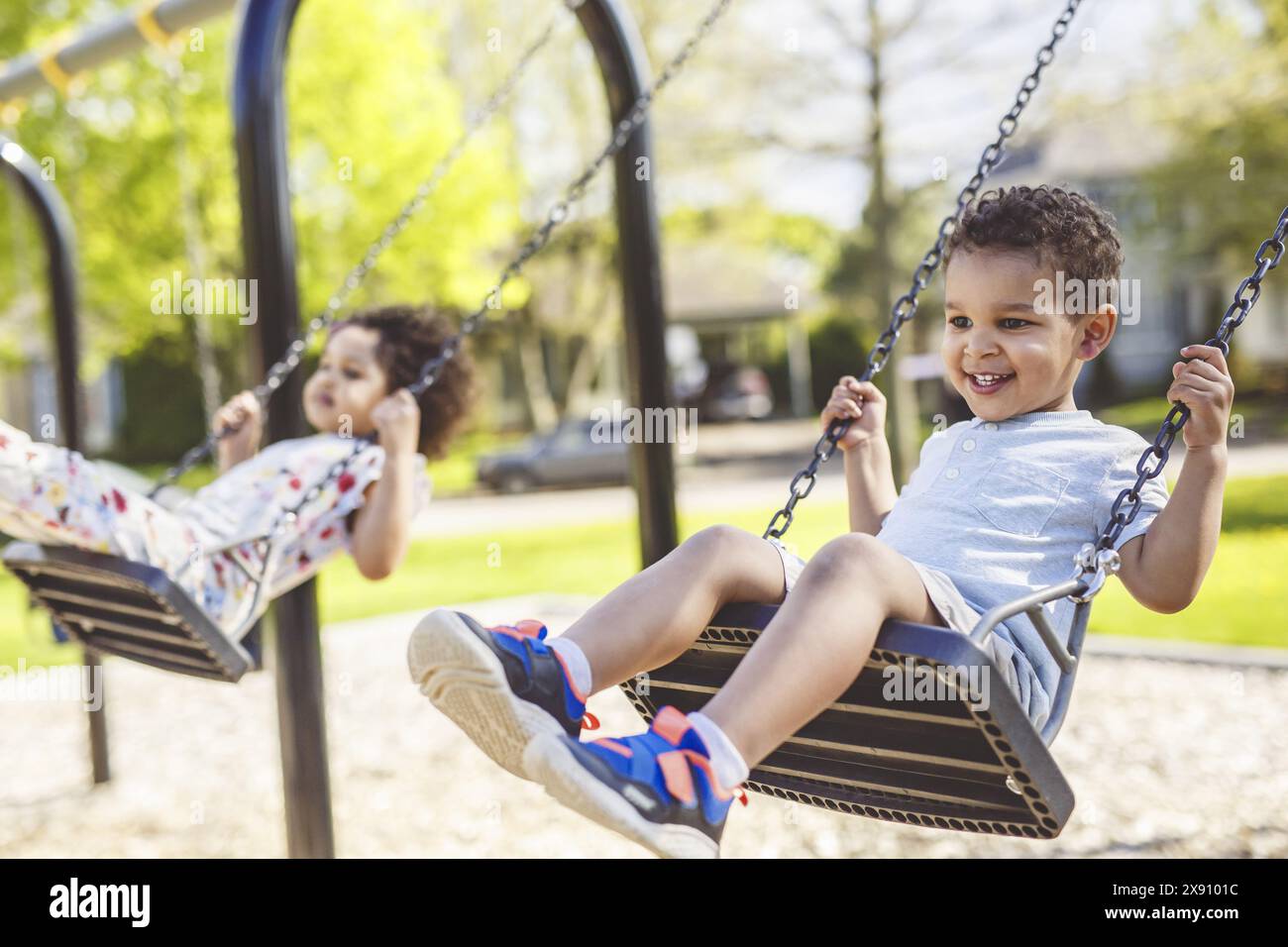 Happy child brother and sister on a swing. Happy kid on playground ...