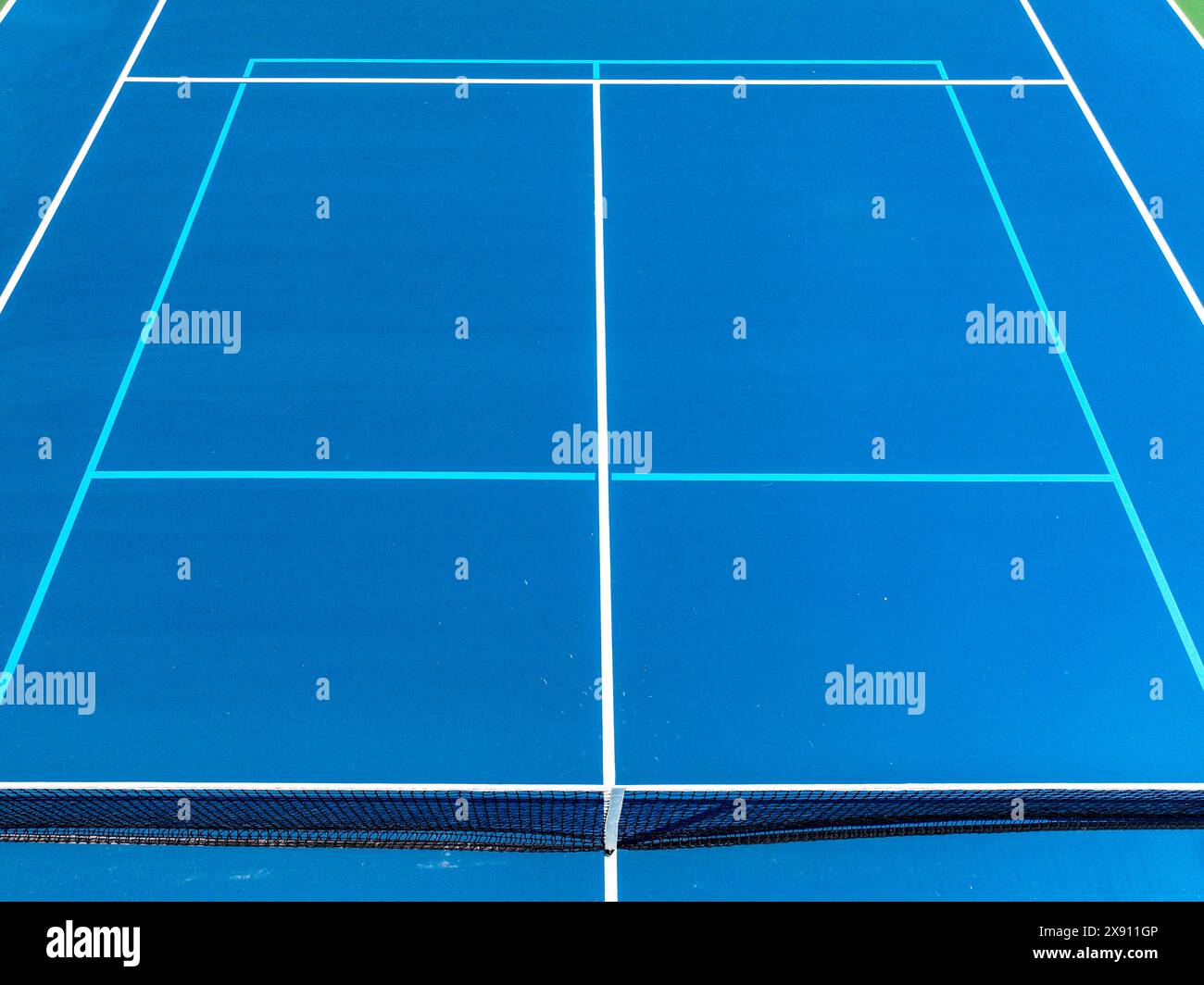 Aerial, drone, photo of new outdoor blue tennis court with white lines combined with light blue pickleball lines. Stock Photo