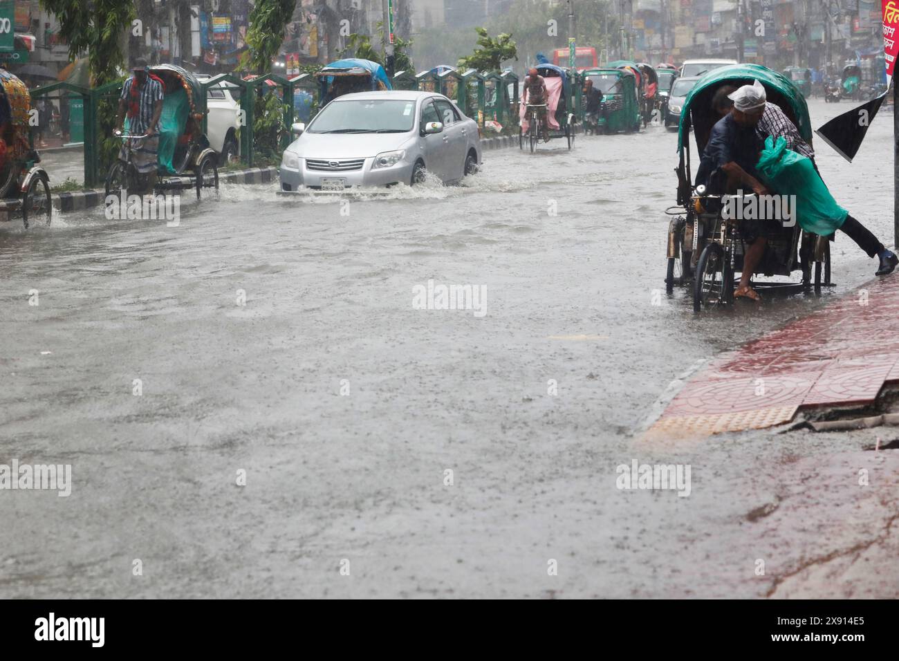 Dhaka, Bangladesh - May 27, 2024: Vehicles try to drive through a flooded street; heavy rain caused by Cyclone Remal caused water logging in various r Stock Photo