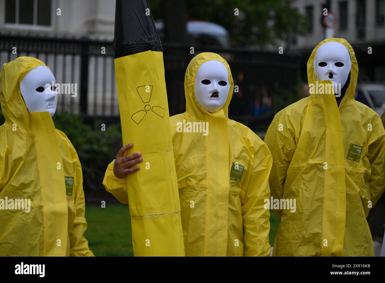 London, England, UK. 28th May, 2024. 25 years after five nuclear bombs were detonated underneath the Ras Koh Hills in Balochistan, activists with the group, Baloch National Movement hold a protest in London. Protesters wearing nuclear protection equipment hold a makeshift nuclear rocket. (Credit Image: © Cal Ford/ZUMA Press Wire) EDITORIAL USAGE ONLY! Not for Commercial USAGE! Stock Photo