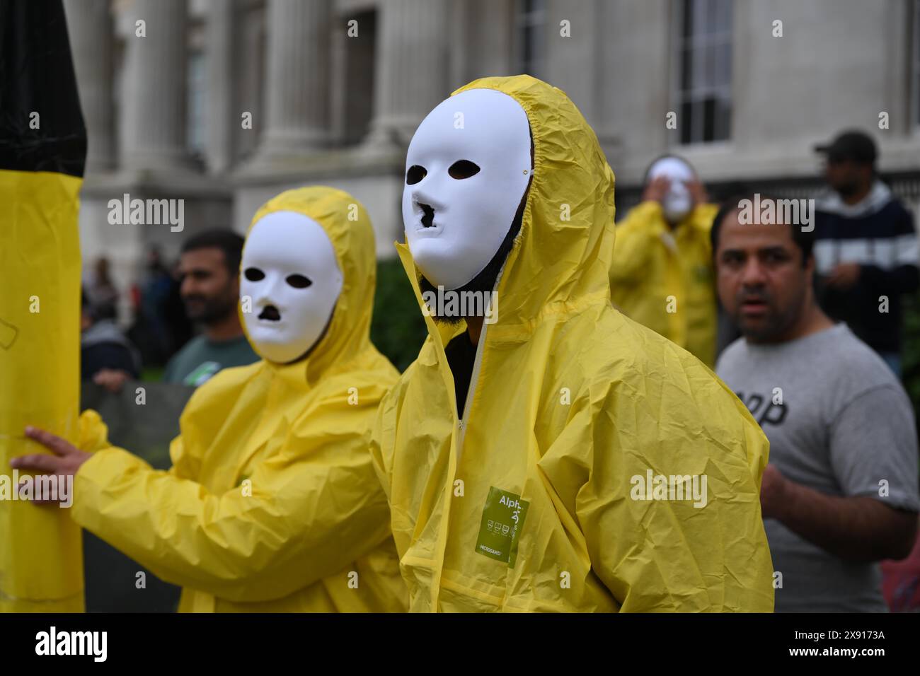 London, England, UK. 28th May, 2024. 25 years after five nuclear bombs were detonated underneath the Ras Koh Hills in Balochistan, activists with the group, Baloch National Movement hold a protest in London. Protesters wearing nuclear protection equipment hold a makeshift nuclear rocket. (Credit Image: © Cal Ford/ZUMA Press Wire) EDITORIAL USAGE ONLY! Not for Commercial USAGE! Stock Photo