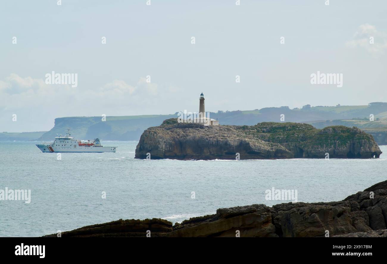 Hospital ship Juan de la Cosa at sea leaving the bay for a rescue practice exercise passing Moors Island and lighthouse Santander Cantabria Spain Stock Photo