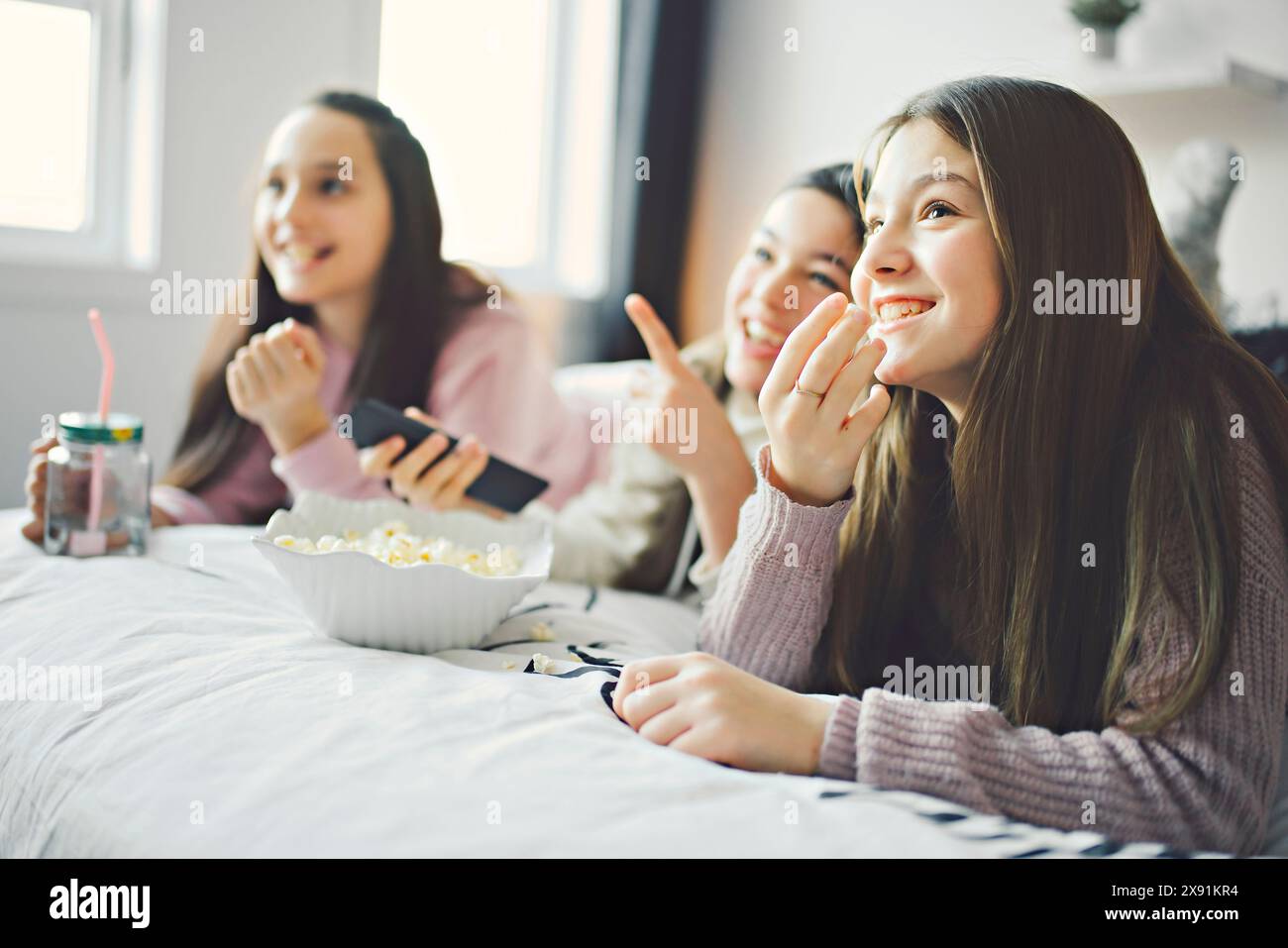 A pajama party with teens eat popcorn on the bed Stock Photo - Alamy