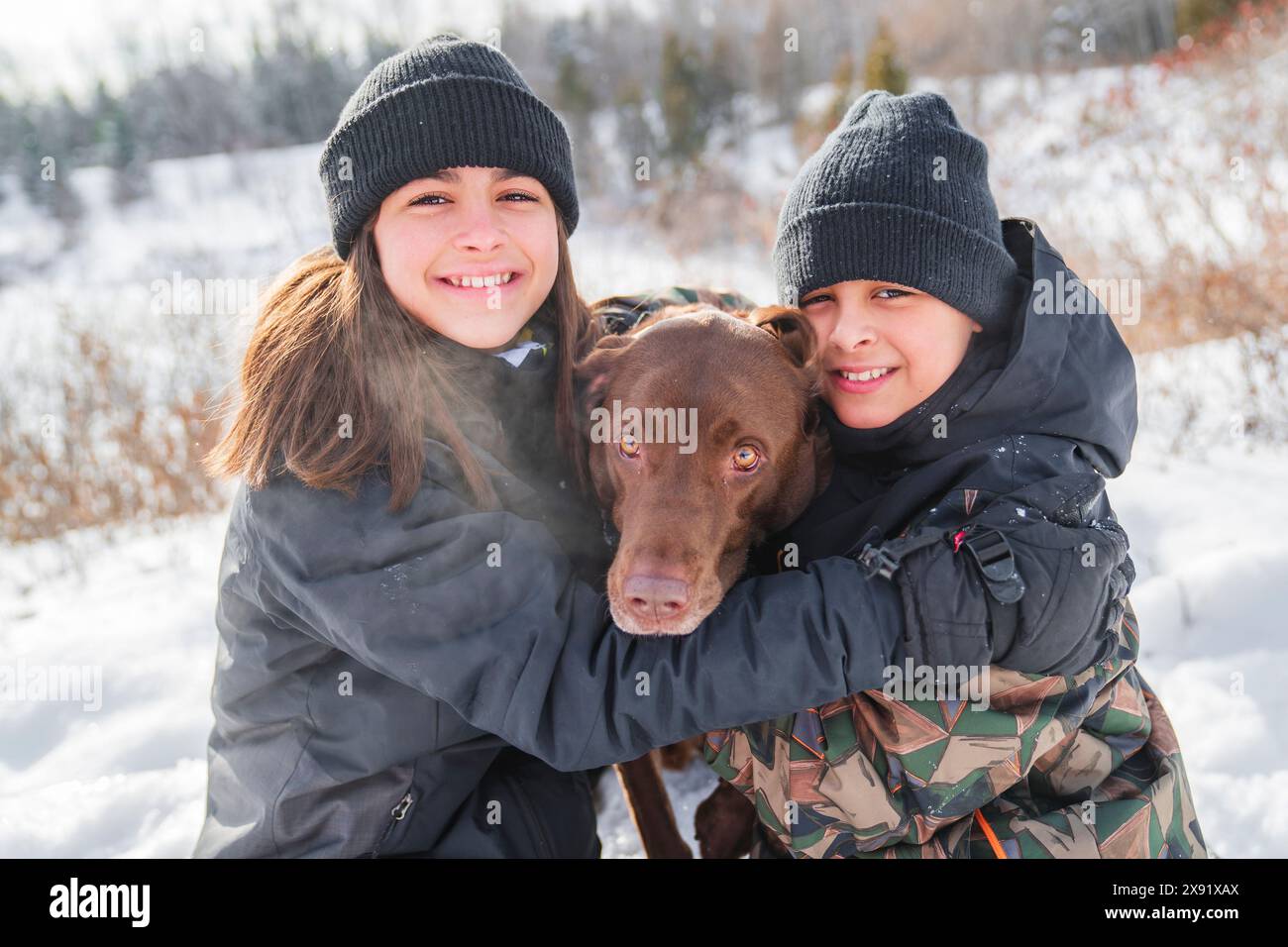 Portrait of brother and sister with labrador dog in winter season Stock Photo