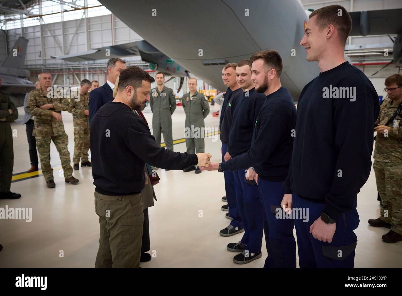 Steenokkerzeel, Belgium. 28th May, 2024. Ukrainian President Volodymyr Zelenskyy, left, hands challenge coins to Ukraine pilots training on the F-16 fighter aircraft at Melsbroek Air Base, May 28, 2024 in Steenokkerzeel, Belgium. Belgium pledged 30 of the advanced multirole fighters in a new bilateral security agreement. Credit: Pool Photo/Ukrainian Presidential Press Office/Alamy Live News Stock Photo
