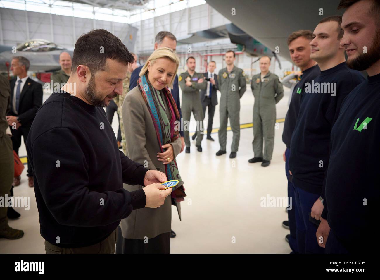 Steenokkerzeel, Belgium. 28th May, 2024. Ukrainian President Volodymyr Zelenskyy, left, and Belgian Defence minister Ludivine Dedonder, center, view a flight patch gifted him by Ukraine pilots training on the F-16 fighter aircraft at Melsbroek Air Base, May 28, 2024 in Steenokkerzeel, Belgium. Belgium pledged 30 of the advanced multirole fighters in a new bilateral security agreement. Credit: Pool Photo/Ukrainian Presidential Press Office/Alamy Live News Stock Photo