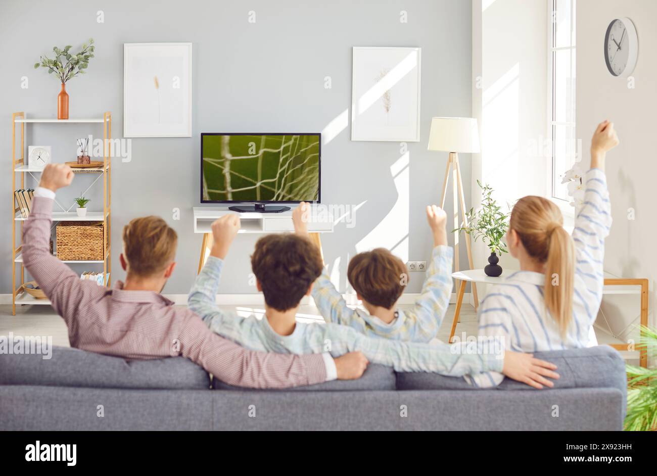 Family fans watching sport football match on tv supporting favorite team at home. Stock Photo
