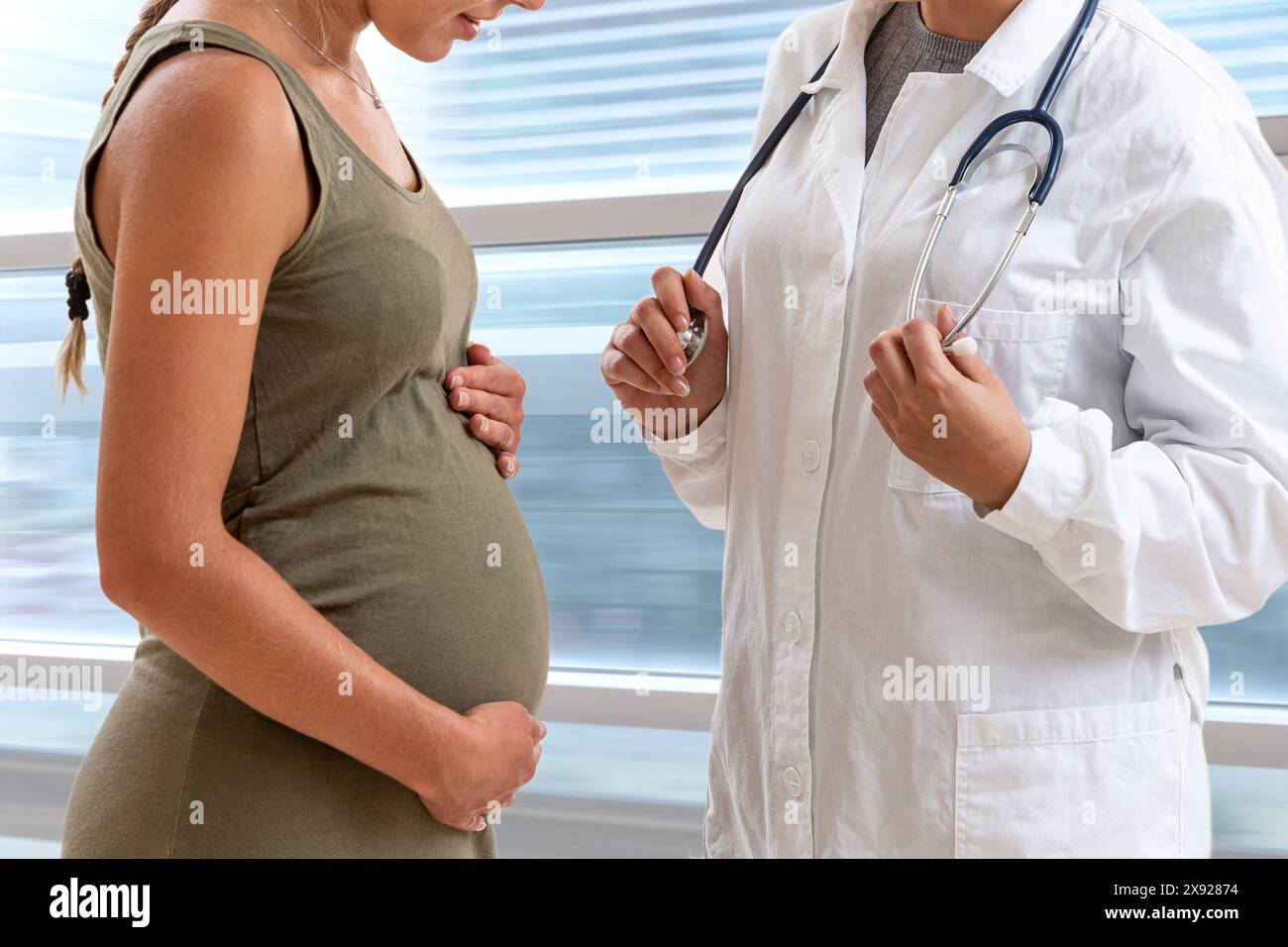 Doctor standing in front of his 7 months pregnant patient. Dialogue of a pregnant woman with her doctor. 016644 037 Stock Photo