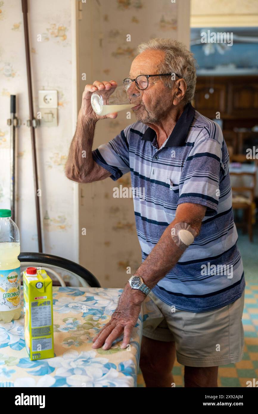 90 year old senior drinking lemonade and wearing a bandage on his left elbow. 90 year old senior 016739 040 Stock Photo