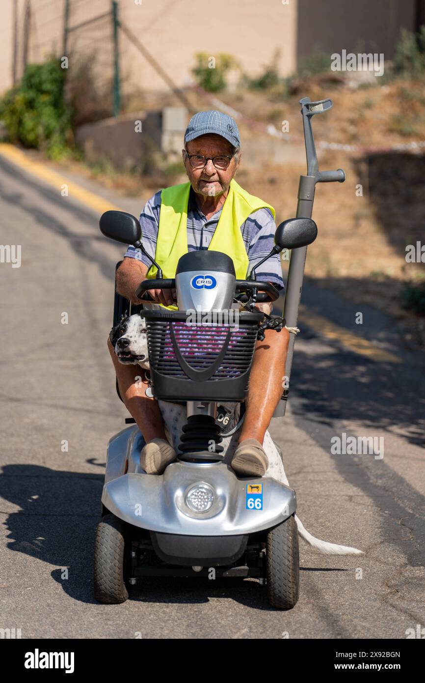 90-year-old senior walking on his electric scooter, with his dog. 90 year old senior on his electric scooter 016739 050 Stock Photo