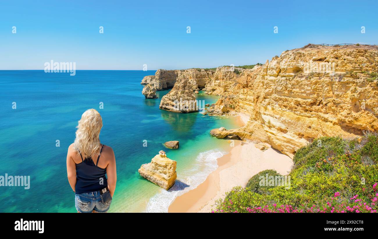 A blonde haired woman looks at the beach and coastline at Praia da Marinha, Algarve, Portugal. Stock Photo