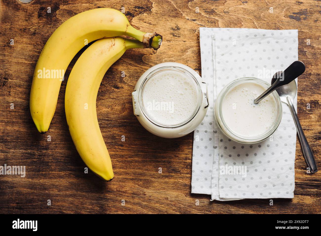 Two jars of banana yogurt on a wooden table. Stock Photo