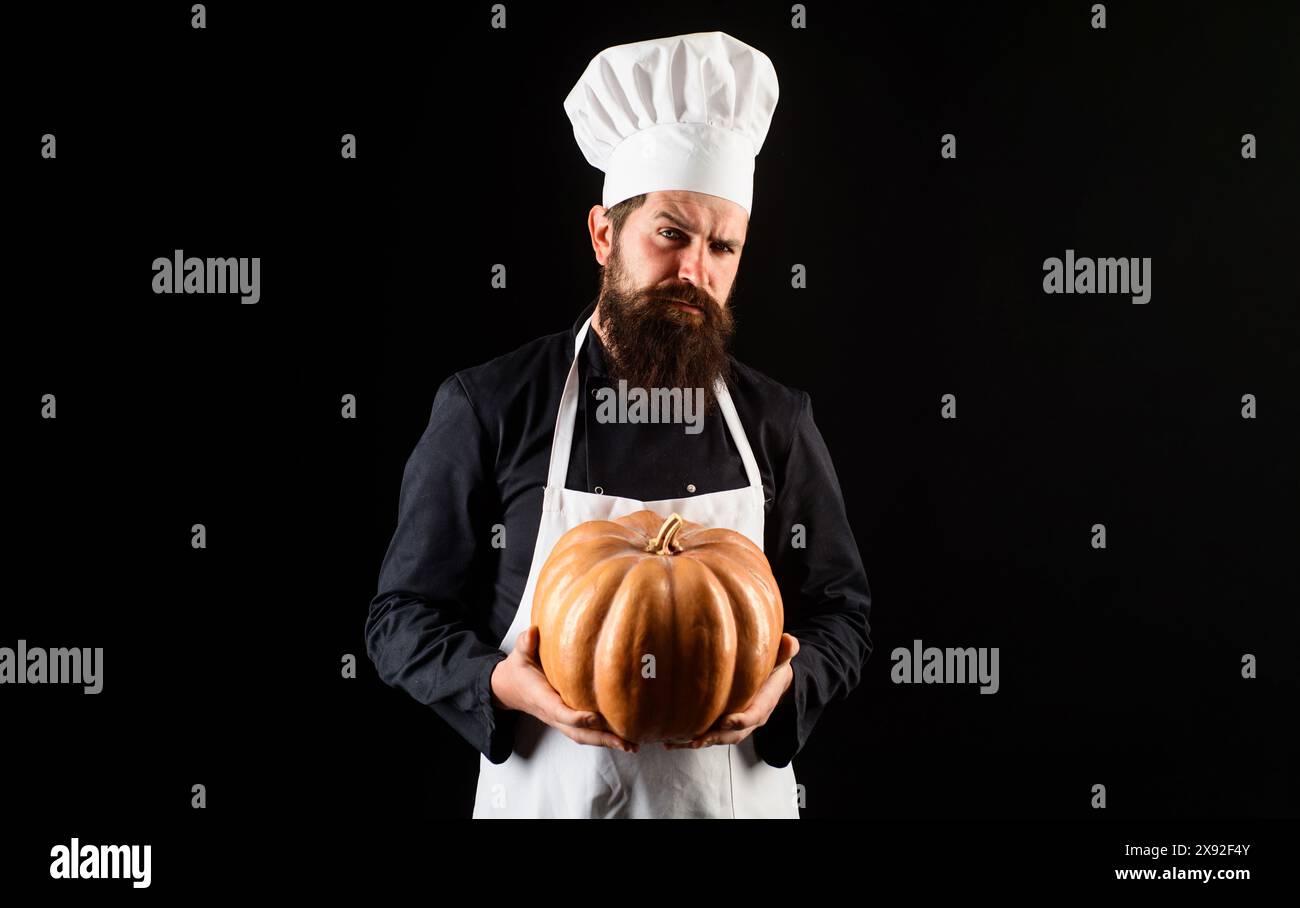 Serious male chef in uniform with pumpkin. Thanksgiving day. Bearded man in chef hat with squash. Cook chef in white apron with pumpkin for cooking Stock Photo