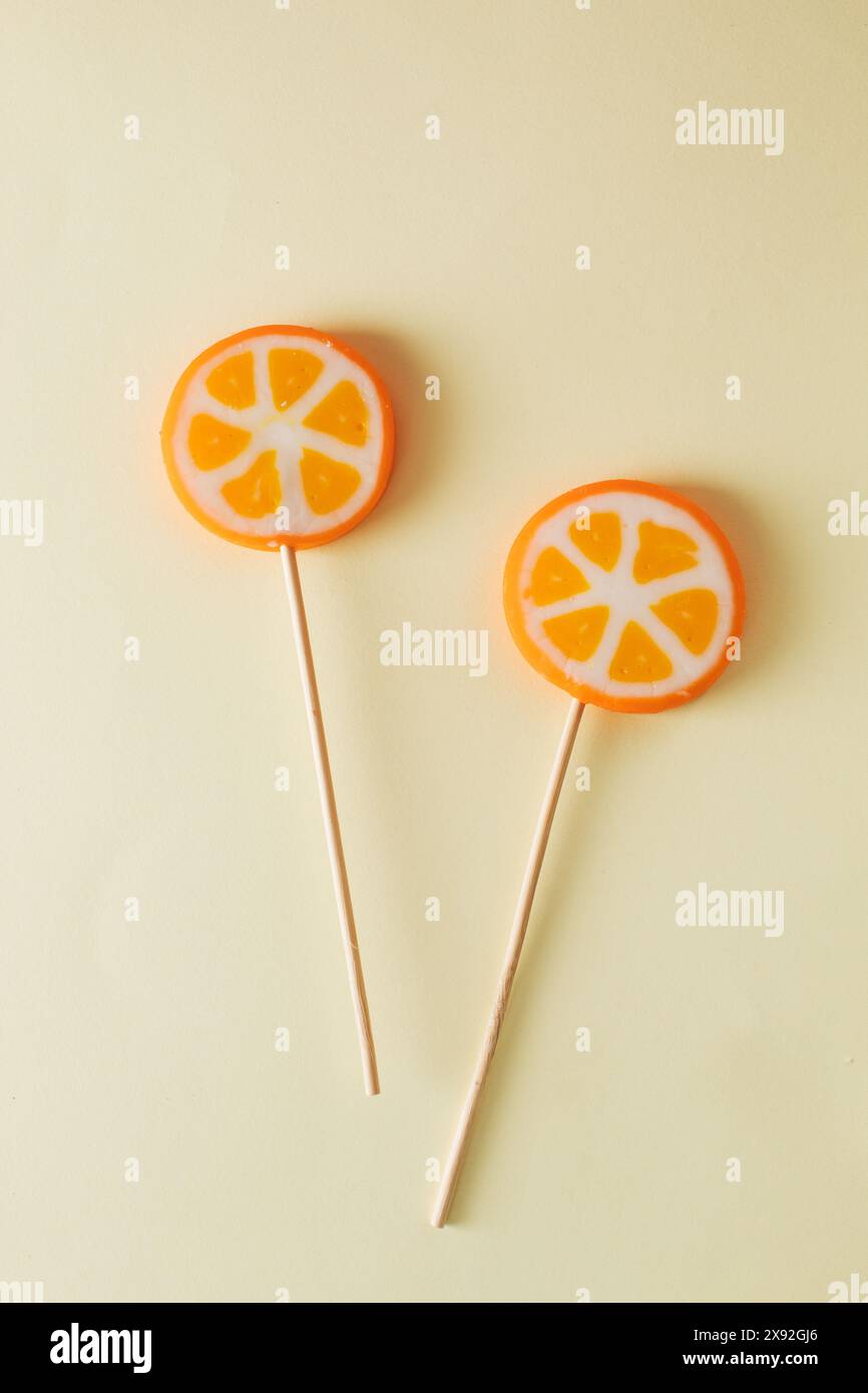 Two orange lollipops on beige background. Minimal concept idea Stock Photo