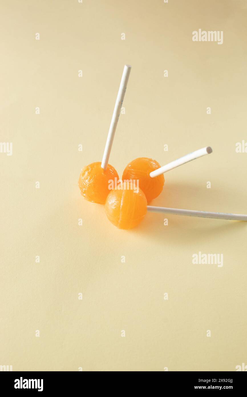 Three orange lollipops on beige background. Minimal concept idea Stock Photo