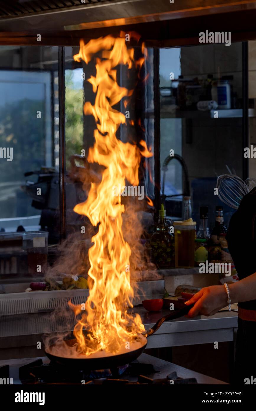 Chef creates flame in pan. Chef cooking with flame in a frying pan on a ...