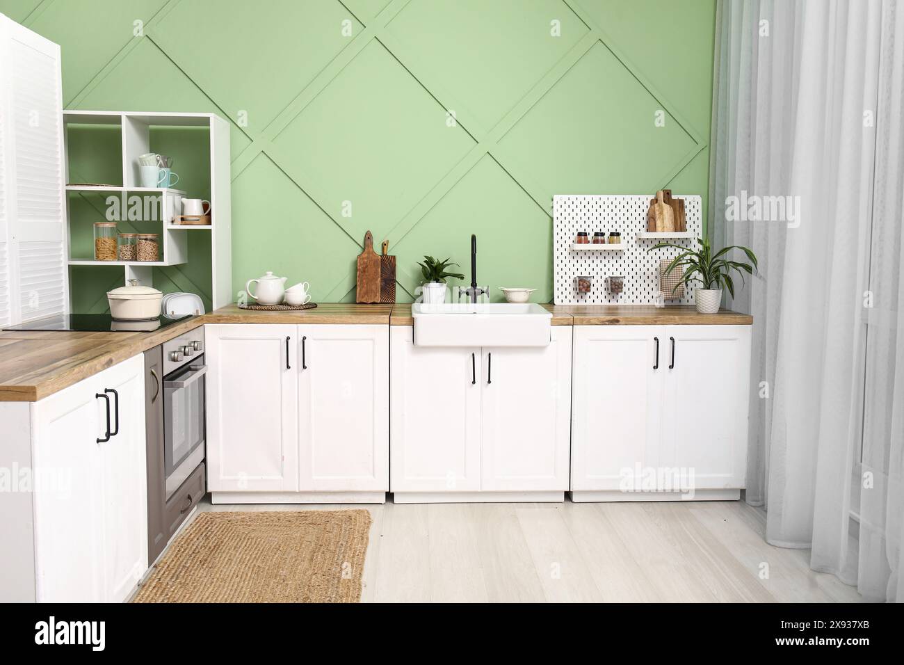 Interior of stylish kitchen with white counters, pegboard and green ...