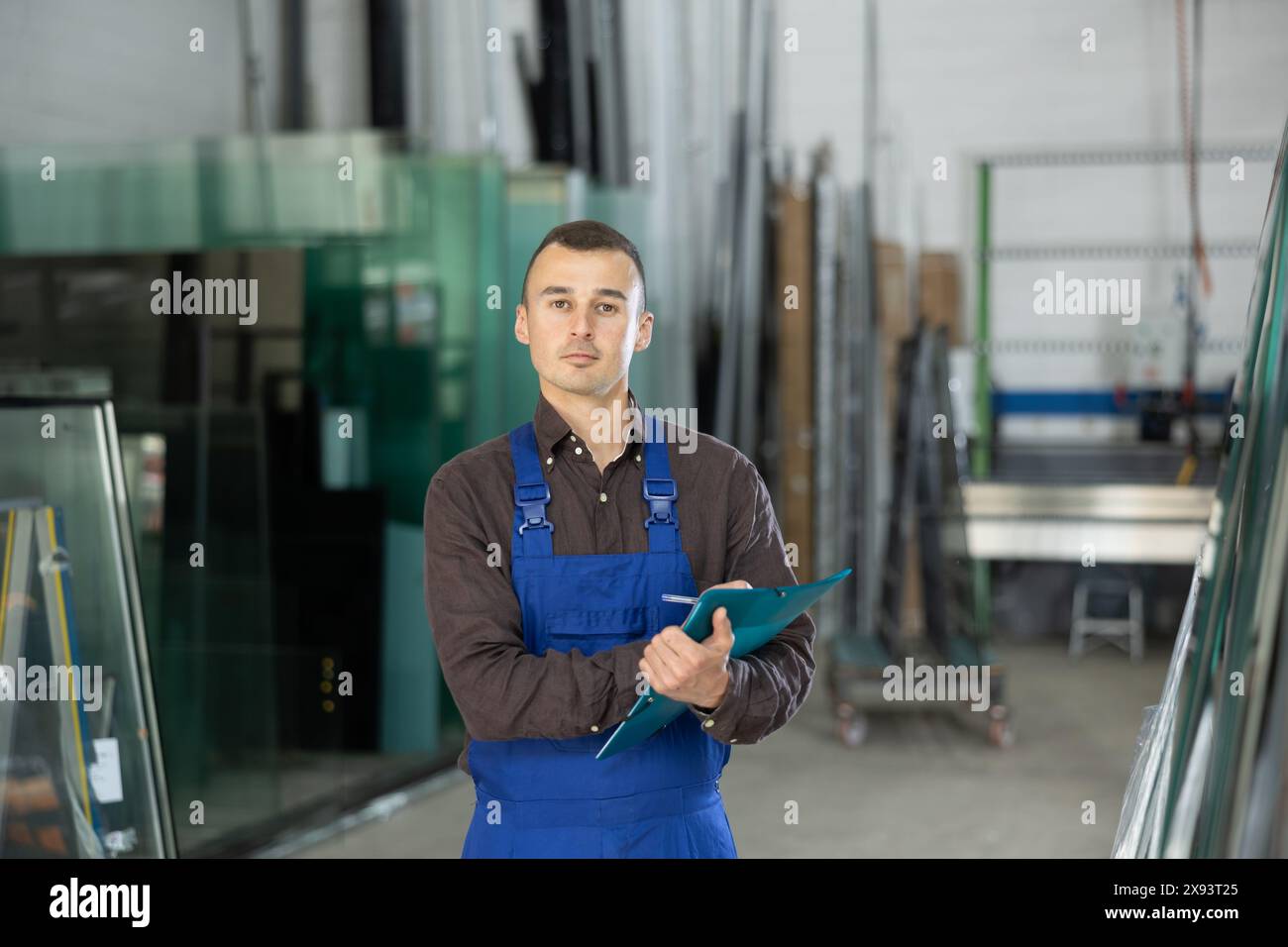 Technician inspecting glass panels and writing notes in workshop Stock Photo