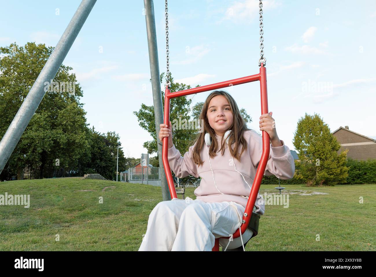 A playground with children's attractions during walks in the park. Girl 10-12 years old on a swing Stock Photo