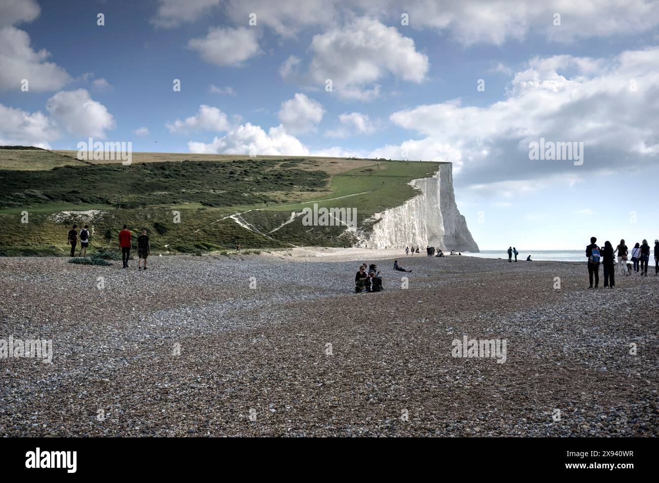 Cuckmere Haven, UK - September 10, 2022: View of Seven Sisters Cliffs on sunny day with clouds showing cliffs, footpath with walkers and numerous peop Stock Photo