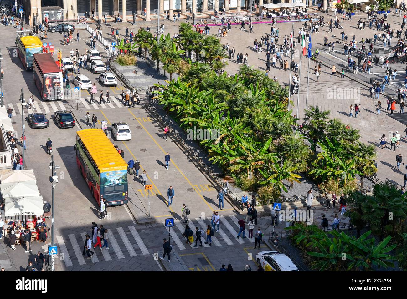 Rooftop view of the west side of Piazza del Duomo with the controversial palms flowerbeds and sightseeing buses full of tourists, Milan, Italy Stock Photo