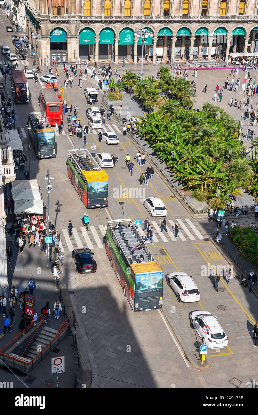 Rooftop view of the west side of Piazza del Duomo with the controversial palms flowerbeds and tour buses full of tourists, Milan, Lombardy, Italy Stock Photo