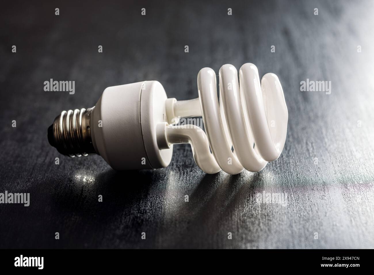 Energy saving light bulb on a black table. Fluorescent Lightbulb Stock Photo