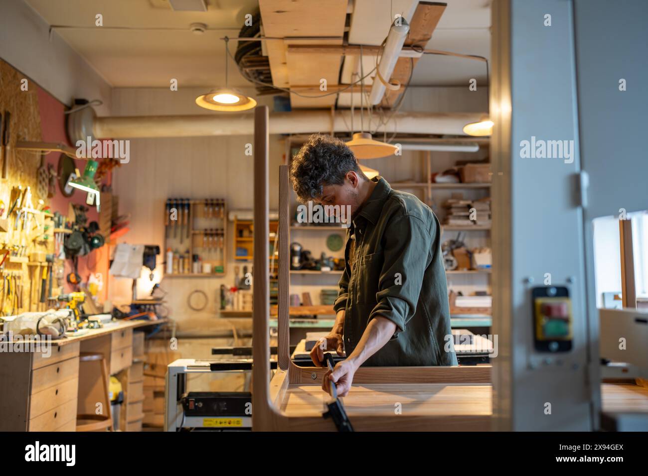 Concentrated carpenter working on making a table, using clamping ...