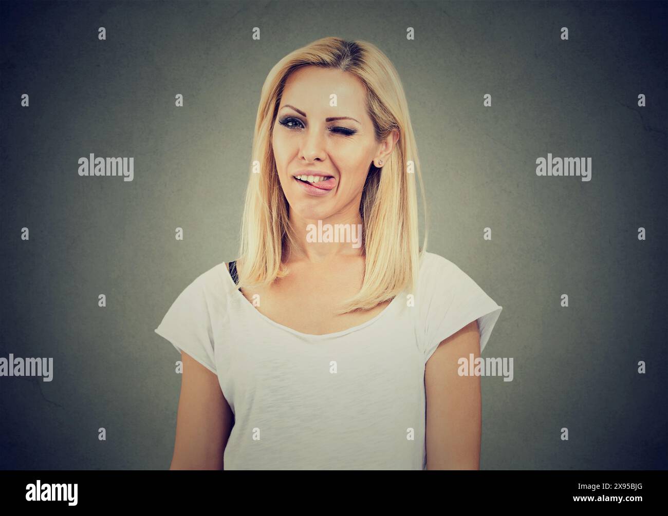 Naughty blond young woman sticking out tongue on camera Stock Photo