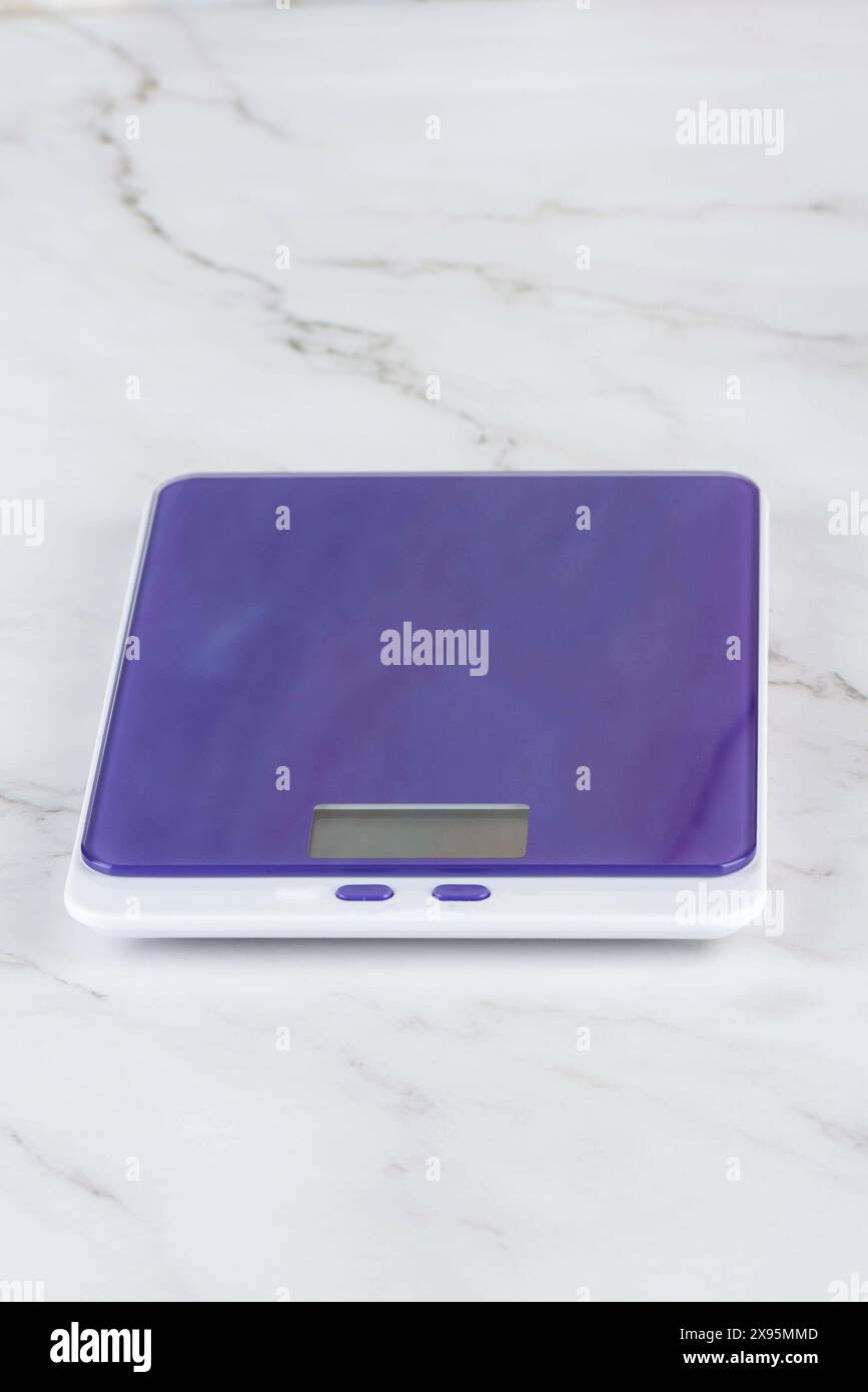 Purple kitchen scale on the kitchen table. Kitchen utensils Stock Photo
