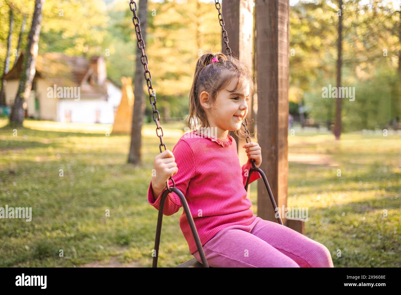 Cute smiling girl on a swing in the playground Stock Photo - Alamy