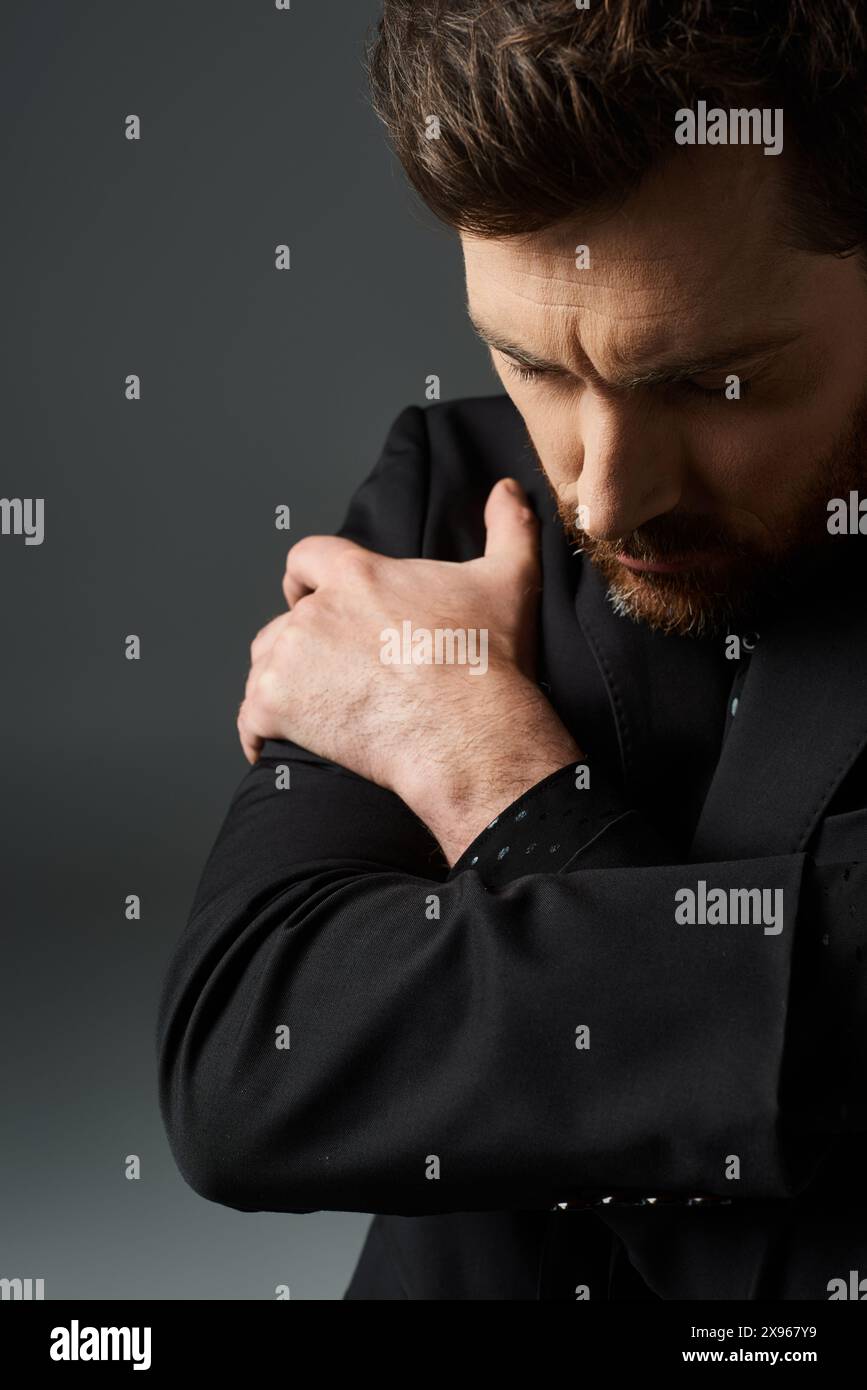 A man in a black suit standing with his hands clasped together Stock ...