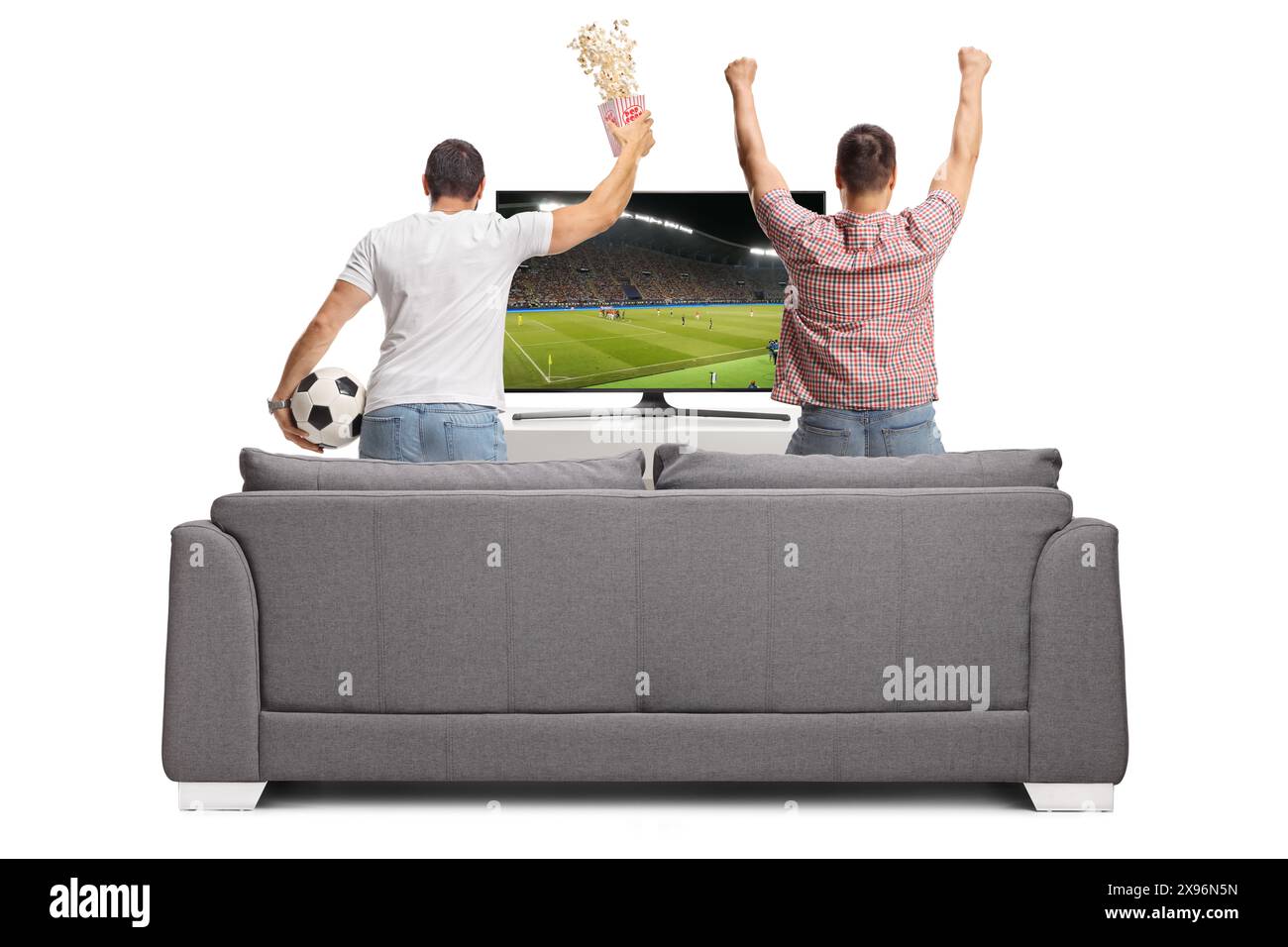 Guys watching football match on tv and cheering in front of a sofa ...