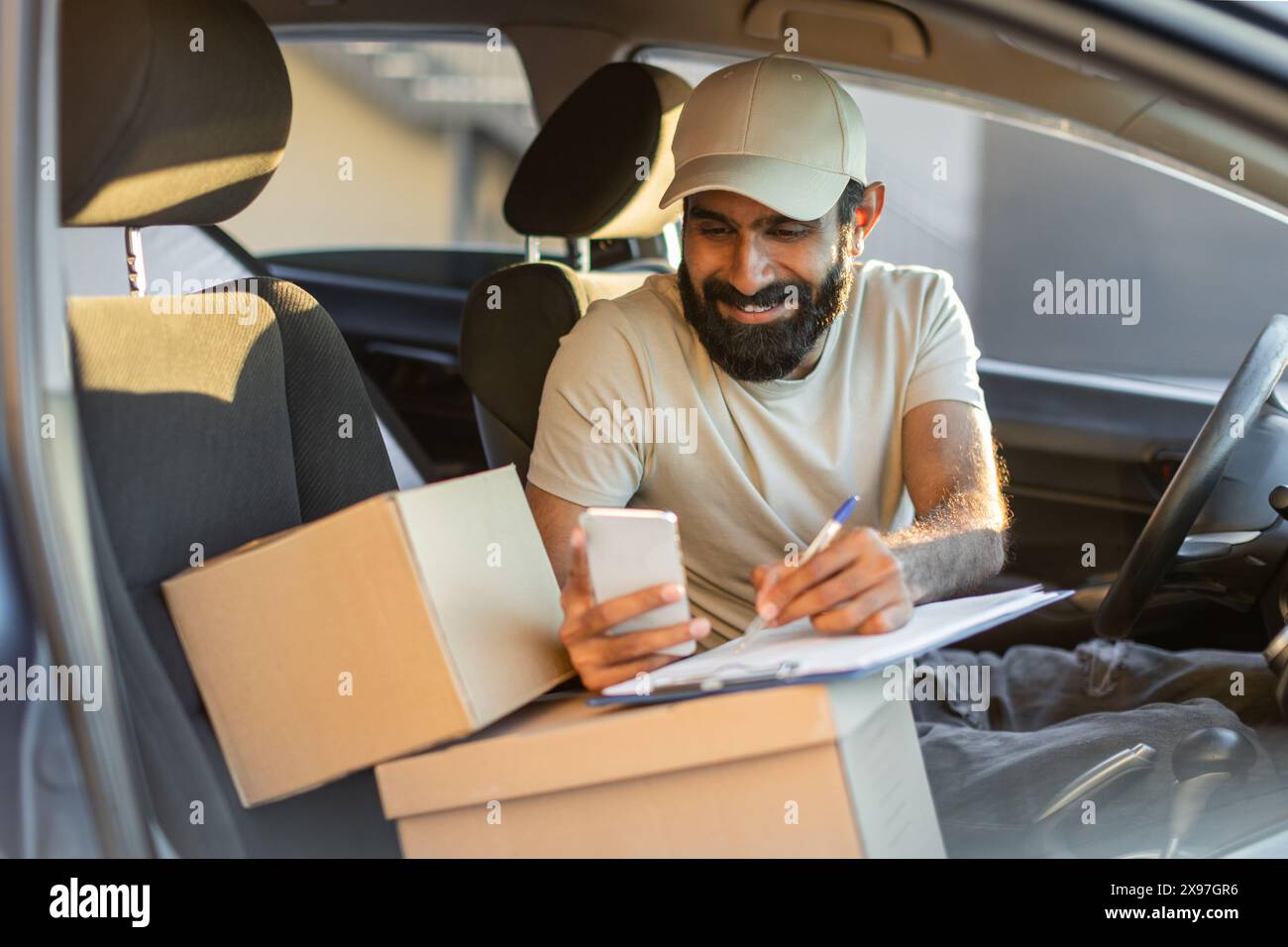 A Delivery Driver With Beard and Cap Checks Delivery Information Stock Photo
