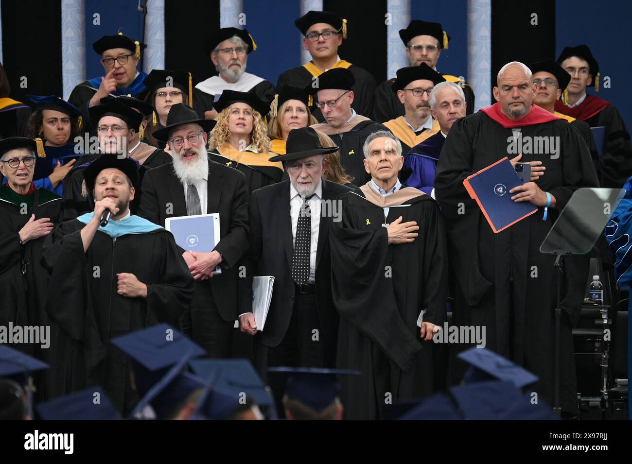 New York, USA. 29th May, 2024. Standing with faculty, Senator John Fetterman (r) (D-PA) attends the commencement ceremony for 2024 Yeshiva University graduating class, at the USTA Billie Jean King National Tennis Center's Louse Armstrong Stadium, Flushing Meadow-Corona Park, Queens, NY, May 29, 2024. (Photo by Anthony Behar/Sipa USA) Credit: Sipa USA/Alamy Live News Stock Photo