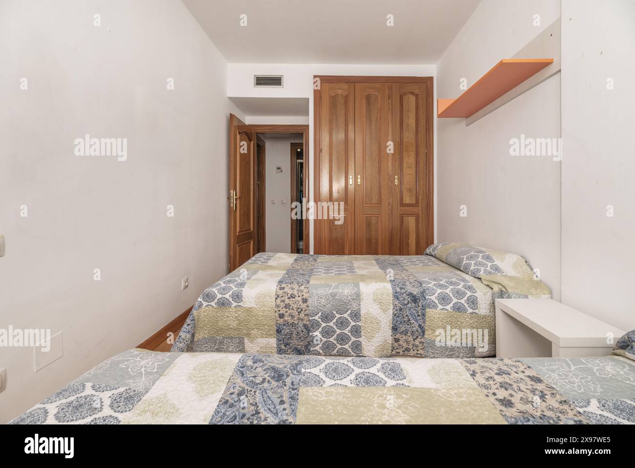 Bedroom with separate twin beds, white painted walls and built-in oak wardrobe Stock Photo