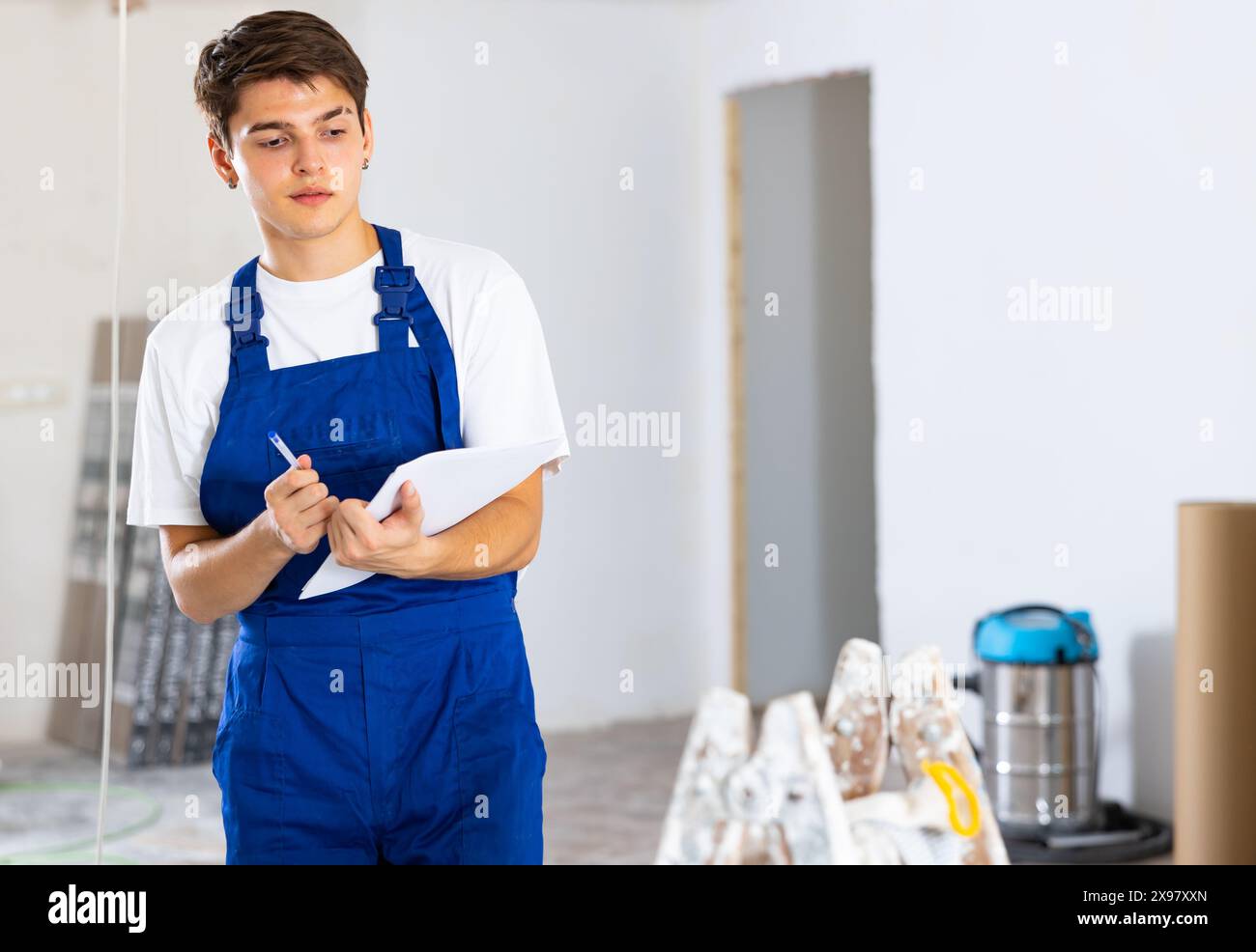 Young builder making checklist while planning indoor building overhaul Stock Photo