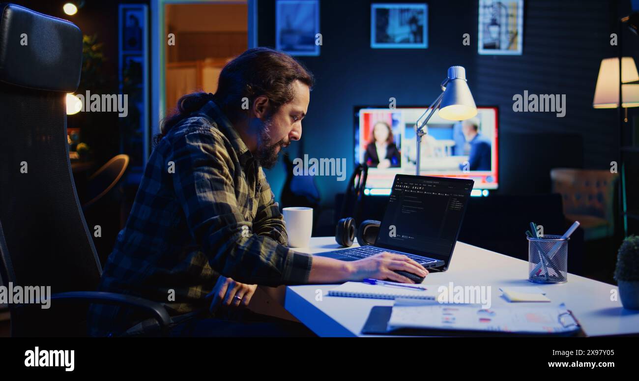 Skilled computer scientist writes code on laptop screen while in living room office using programming languages. Self employed IT specialist working on fixing database errors from home, camera B Stock Photo