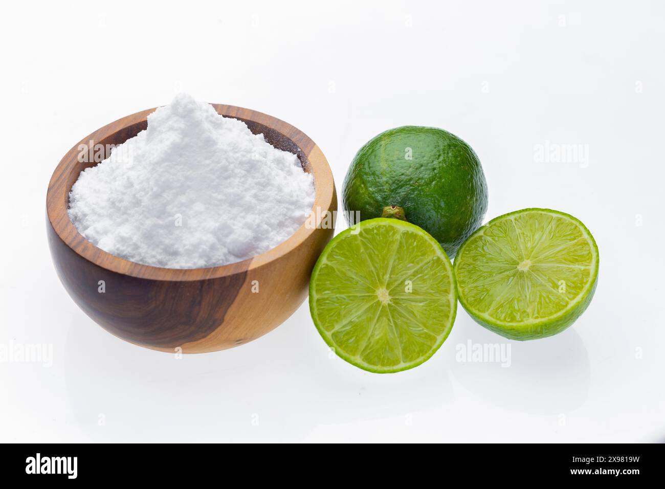 Baking soda in wooden container and lime, isolated on white Stock Photo